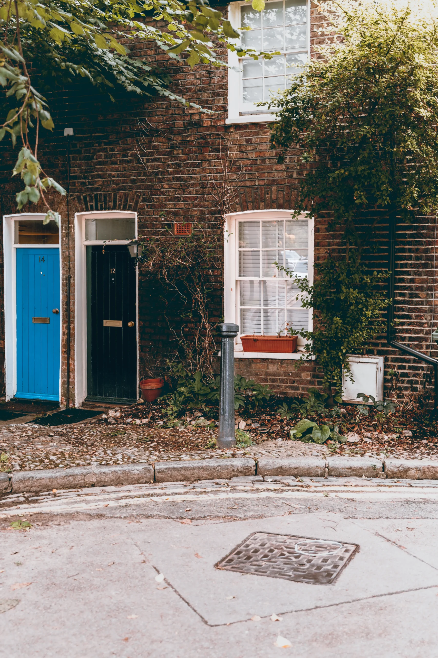 Two traditional brick houses with a blue and black door side by side.